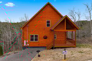 Beautiful log cabin retreat nestled in peaceful wooded surroundings with covered porch and mountain backdrop.