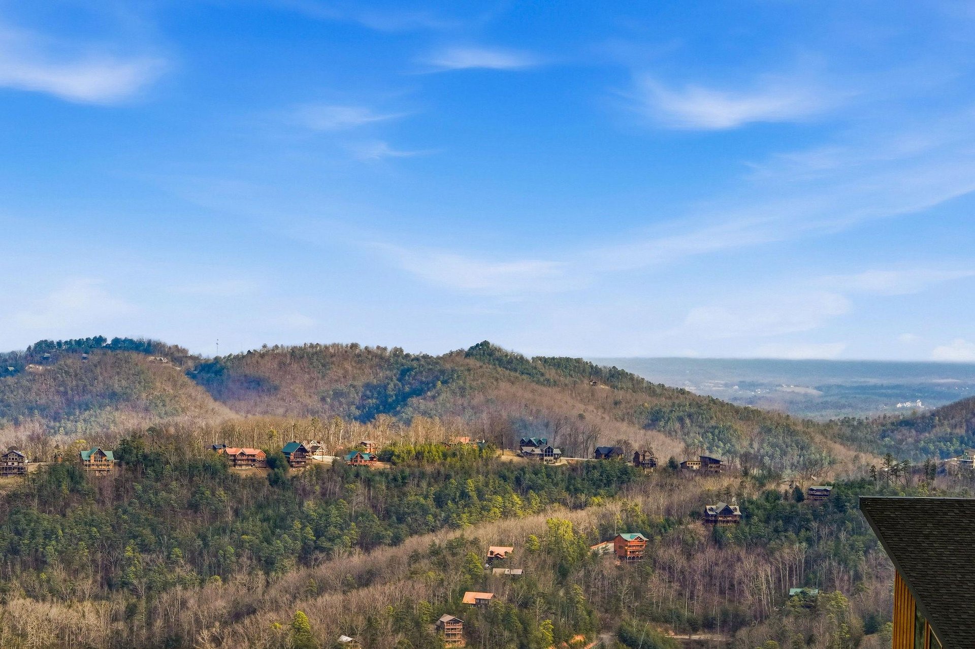 Stunning mountain panorama showcases rolling Appalachian foothills dotted with cabins under expansive blue skies.