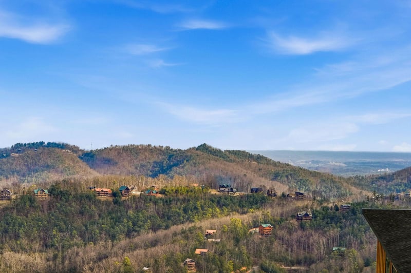 Stunning mountain panorama showcases rolling Appalachian foothills dotted with cabins under expansive blue skies.