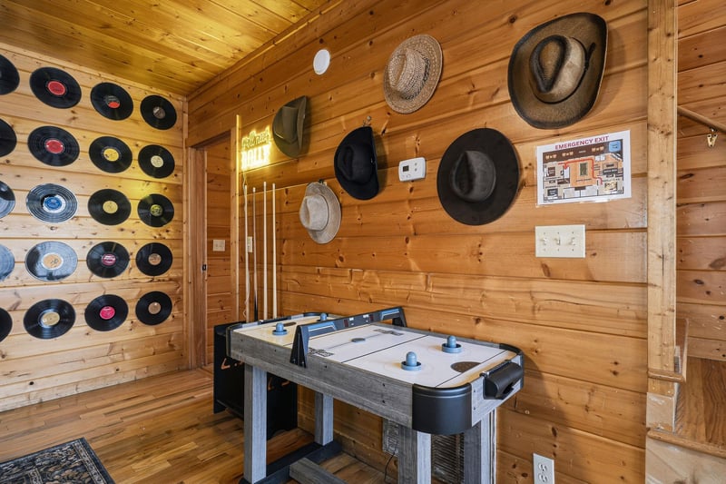 Step into your rustic game room where vintage vinyl records create a nostalgic backdrop for air hockey matches beneath warm wood beams.