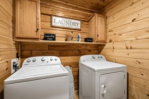 Your private laundry room features fullsize washer and dryer with rustic wood cabinetry and thoughtful storage for all your linens.