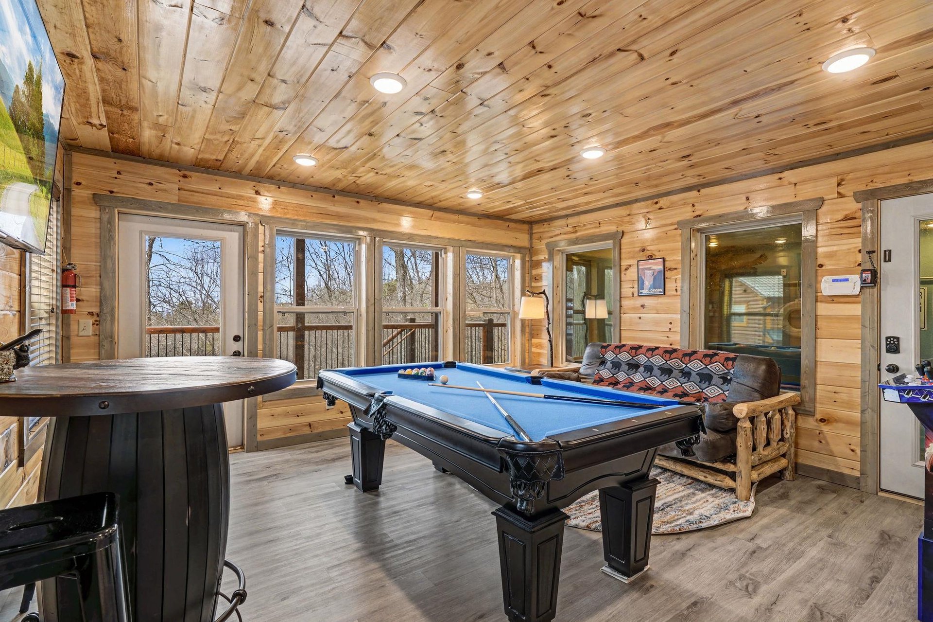 Sink into cozy seating and enjoy hours of pool games in this stunning game room with forest views.