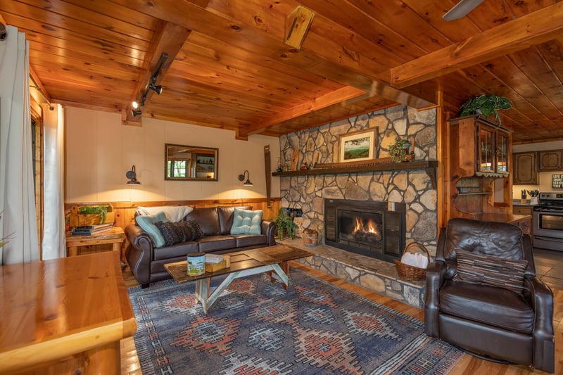 Fireplace, sofa, coffee table, and chair at Hidden Pleasure, a 1bedroom cabin rental located in Gatlinburg