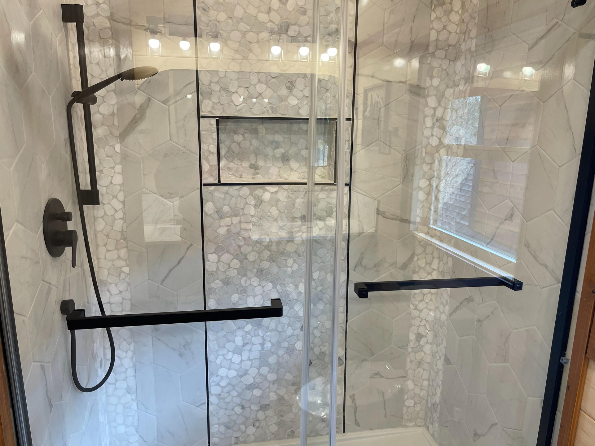 Step into your luxurious marble shower with elegant mosaic accents and sleek glass doors for a spalike experience.