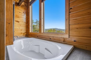 Soak away stress in your private tub with stunning mountain views framing the moment. Natural wood walls and abundant sunlight create a serene retreat for ultimate relaxation.