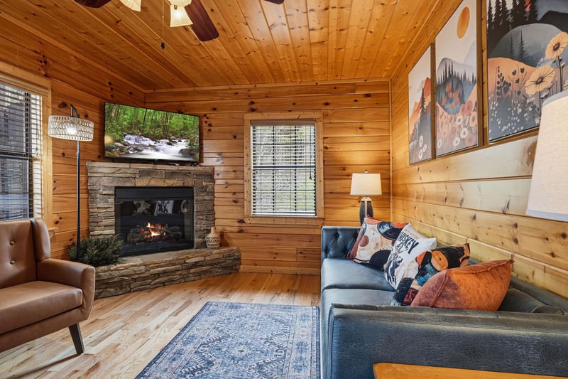 Sink into the cozy sectional sofa while the stone fireplace crackles warmly, creating your perfect cabin retreat.
