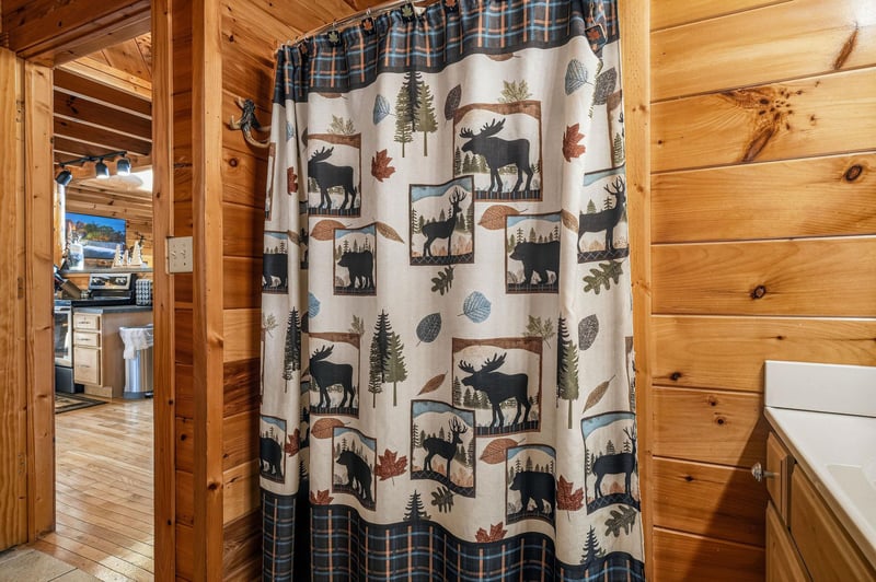 Step into your cozy, rusticthemed bathroom with charming woodlandinspired details. The warm pine walls and naturethemed shower curtain create a cabinlike retreat perfect for unwinding after your a