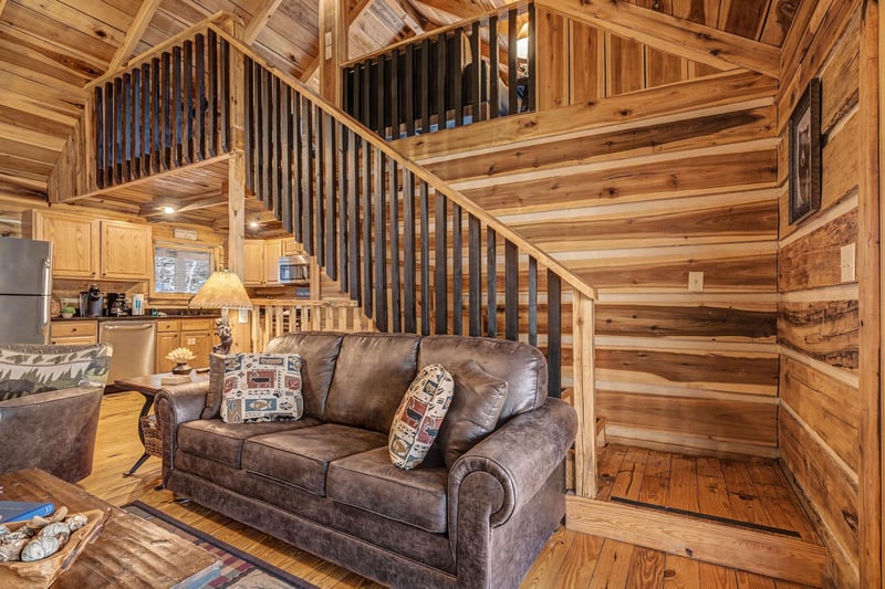 Relax in your cozy log cabin living room with comfortable leather seating and rustic wood details throughout.