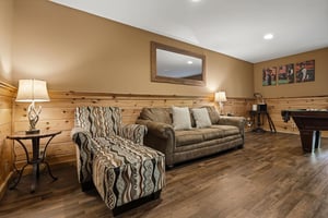 Settle into your cozy living room with warm wood paneling, comfortable seating, and entertainment options for memorable evenings together.