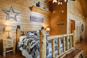 Sink into rustic luxury in your cozy log bedroom, where warm wood walls, charming cabin décor, and soft bedside lighting invite you to unwind and rest easy.