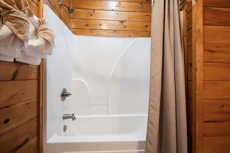Your private bath features warm wood accents and a tubshower combo, with soft towels and a cozy robe ready for your relaxation.
