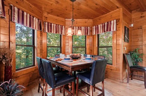 Gather around this handsome dining table, where warm wood and forest views create the perfect setting for your morning coffee or evening meal.