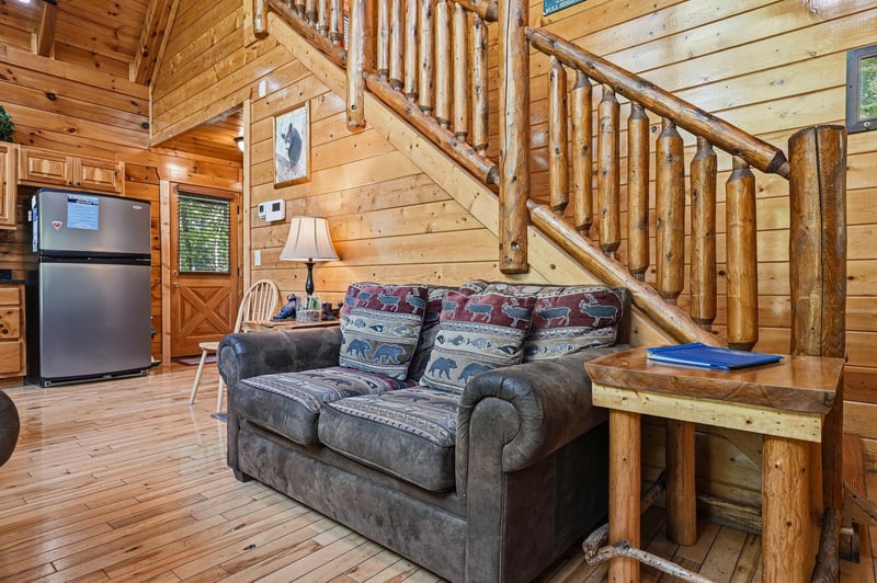 Curl up on the cozy sofa and admire the stunning log staircase, where rustic craftsmanship meets inviting warmth in this charming cabin retreat.