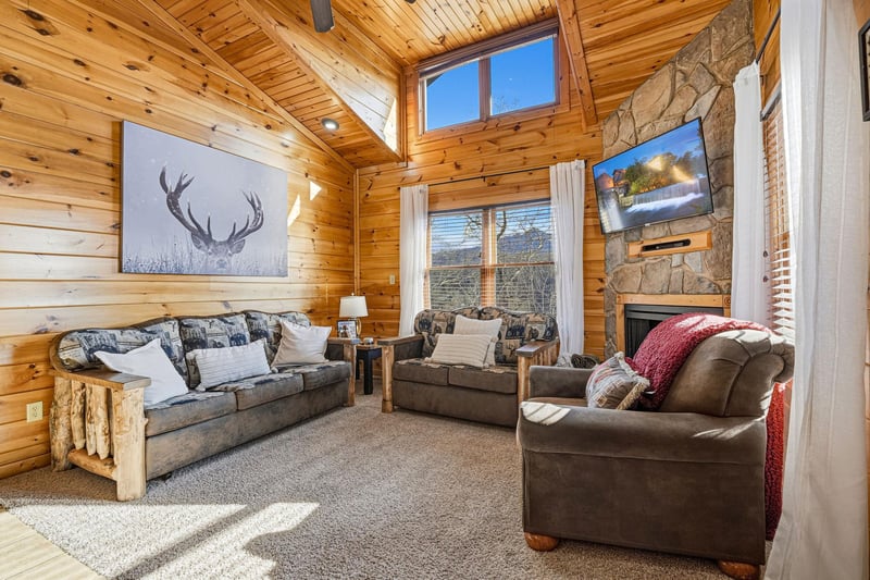 Sink into plush seating surrounded by warm wood and rustic charm, where your stone fireplace crackles beneath soaring ceilings and natural light.