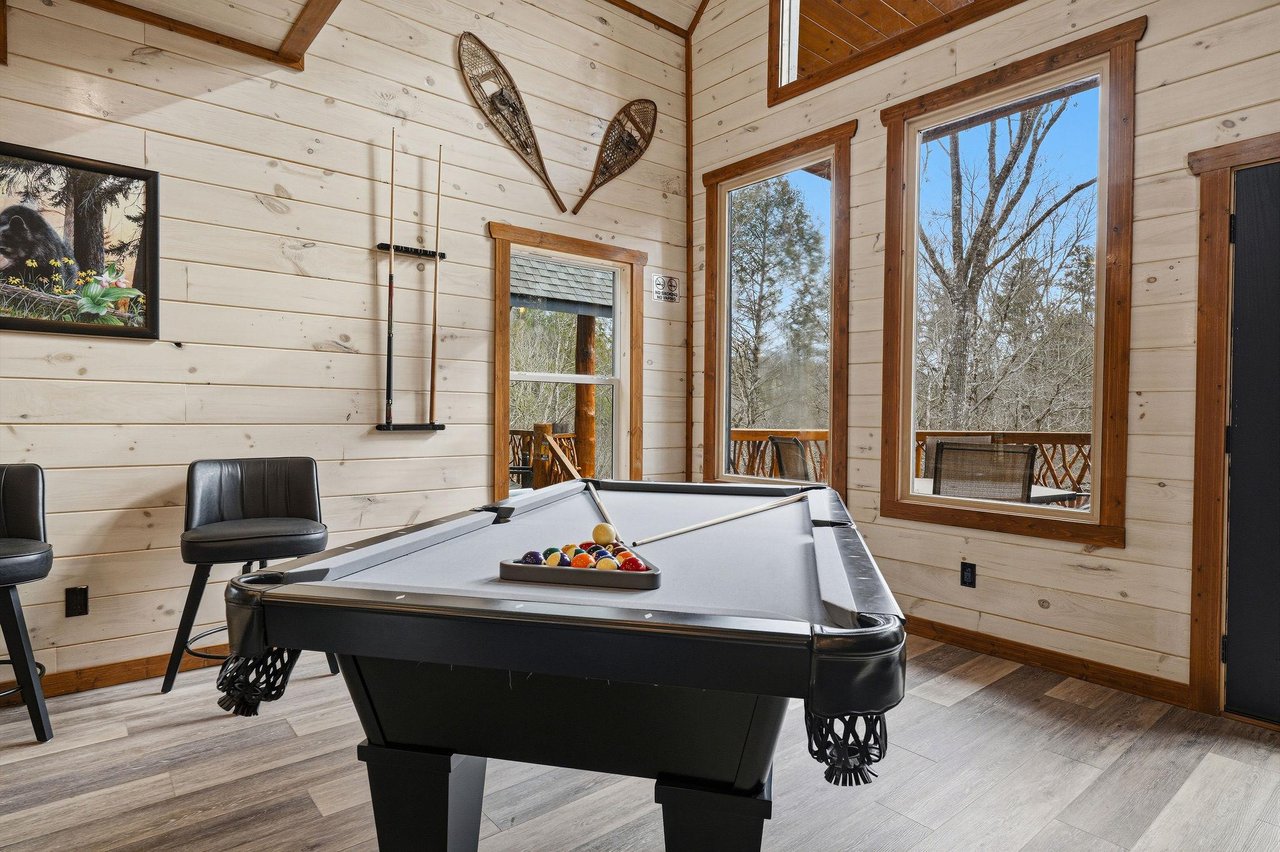 Your game room retreat awaits with a premium pool table, rustic charm, and nature views through every window.