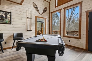 Your game room retreat awaits with a premium pool table, rustic charm, and nature views through every window.