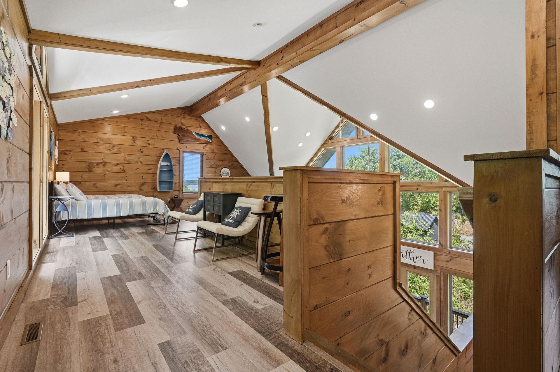 Cozy loft bedroom with exposed wood beams and large windows offering natural light for your peaceful retreat.