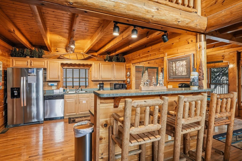 Step into your cozy mountain retreat where rustic log beams frame a fullyequipped kitchen with modern stainless appliances. Gather around the handcrafted log bar stools for meals and memories.