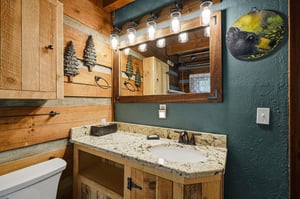 Step into your private bathroom featuring rustic wood accents, granite countertops, and charming cabininspired décor that brings mountain serenity to your morning routine.