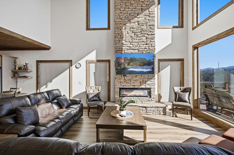 Relax in your stunning living room with soaring ceilings, stone fireplace, and panoramic mountain views through floortoceiling windows.