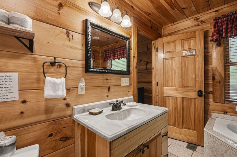 Step into your private rustic bathroom, where warm knotted pine walls and soft lighting create a cozy cabin feel. Fresh towels await you, and every detail invites relaxation.
