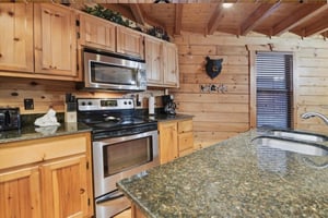 Your fully equipped kitchen features granite counters, stainless appliances, and rustic log cabin charm perfect for preparing meals.