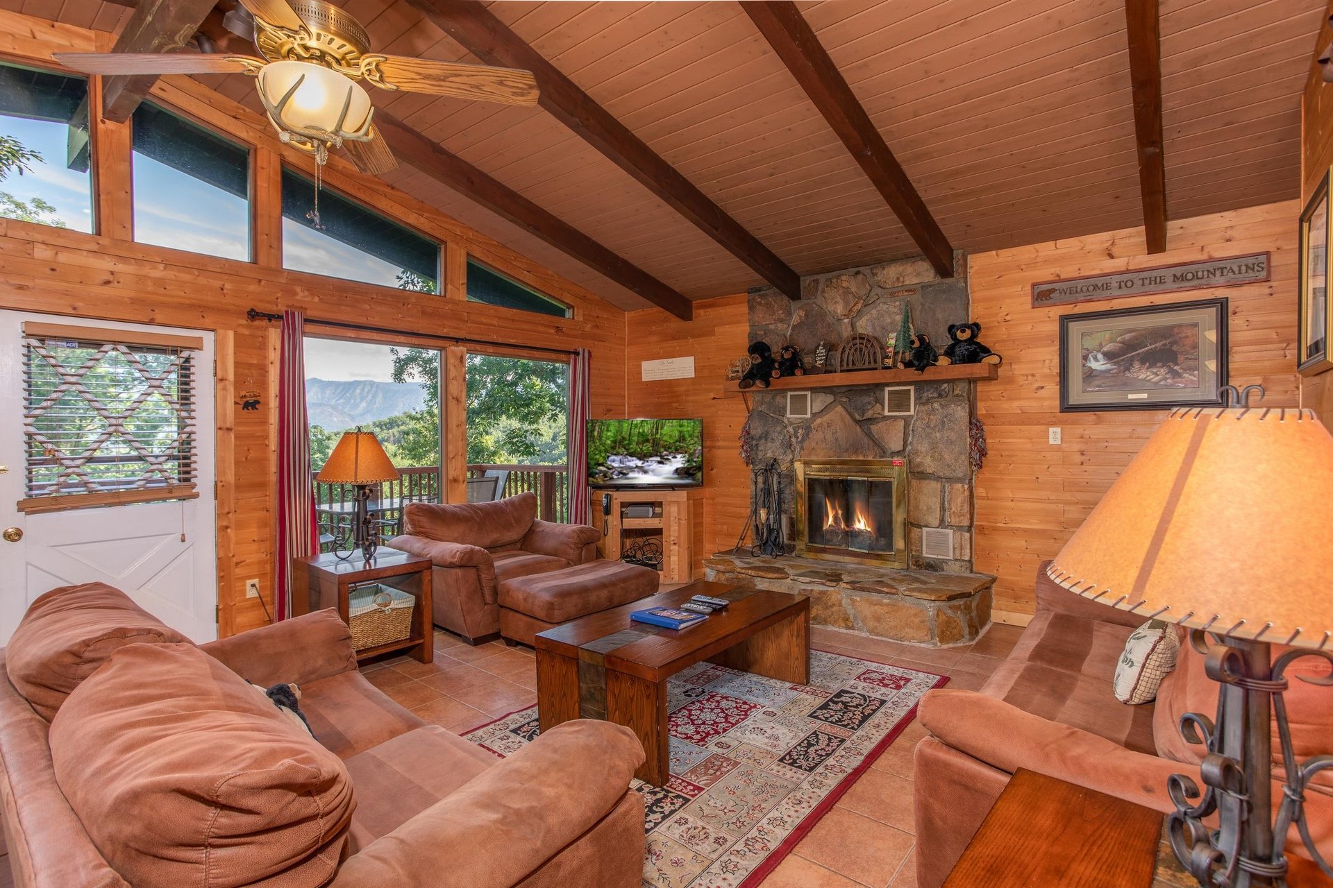 Living room with couch, loveseat, and chair, floortoceiling windows, and a fireplace at Bushwood Lodge, a 3bedroom cabin rental located in Gatlinburg