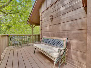 Relax on your private deck with a cushioned bench and bistro table, surrounded by lush green forest views.
