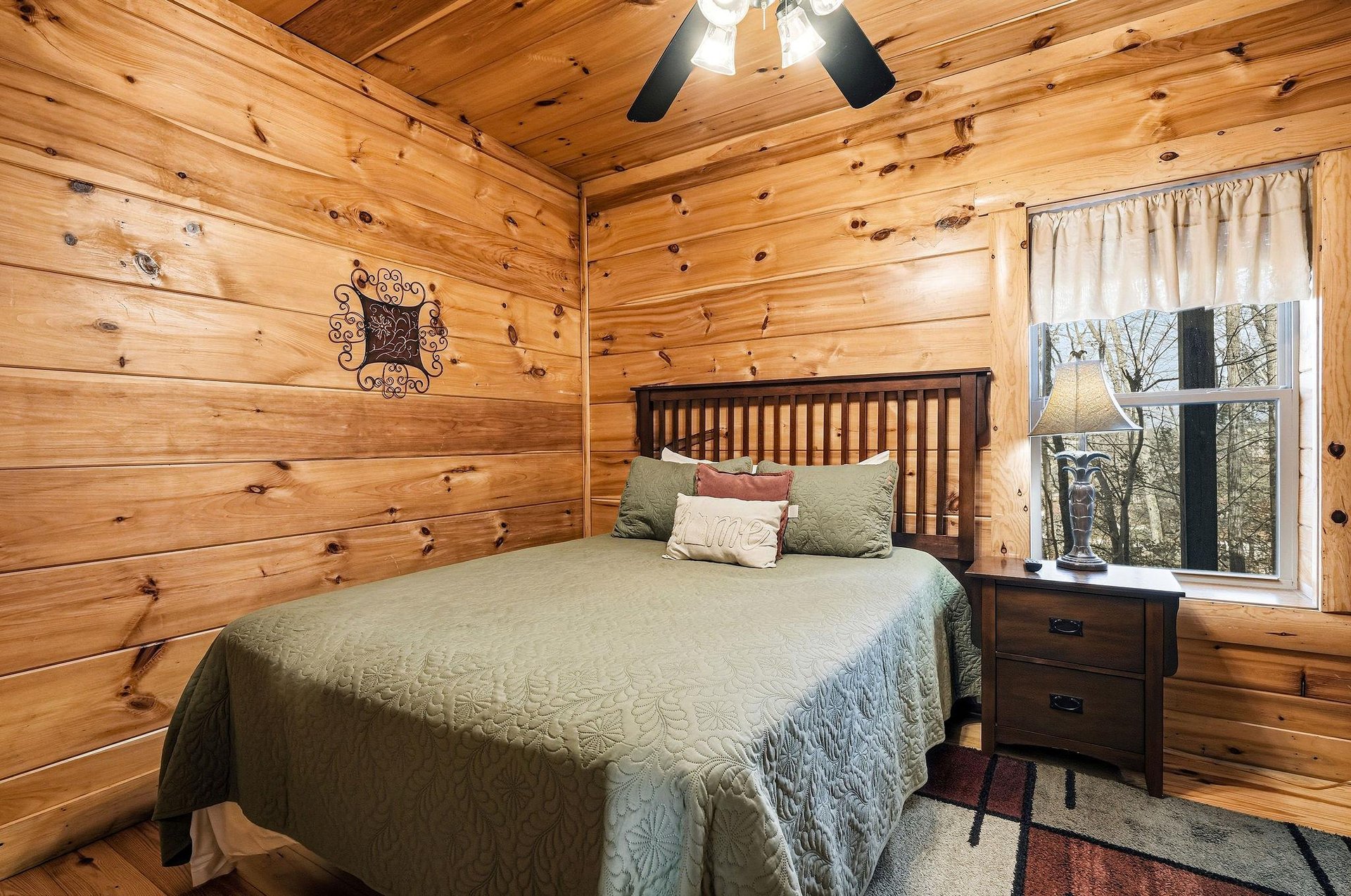 Cozy log cabin bedroom with warm wood walls wraps you in rustic comfort. Wake to forest views from your window.