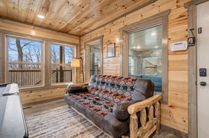 Cozy up on this rustic leather sofa surrounded by warm wood walls, with forest views and your private hot tub just steps away.