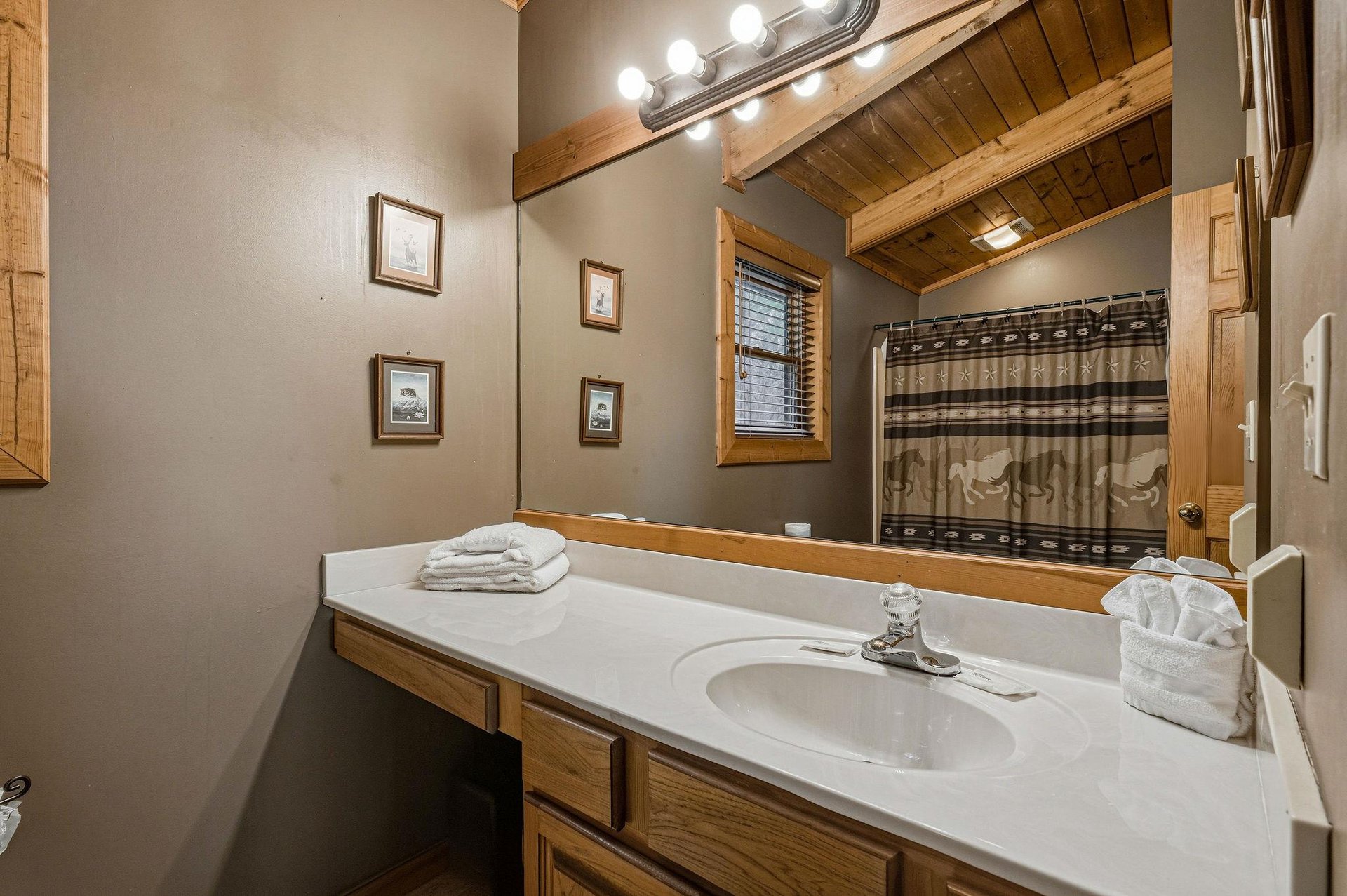 Your private bathroom features rustic wood details, bright vanity lighting, and fresh towels for your comfort.