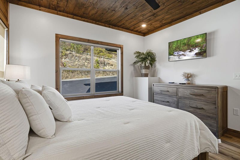 Drift into peaceful sleep beneath rustic wood ceilings in your serene bedroom, where natural textures and calming artwork create the perfect retreat.