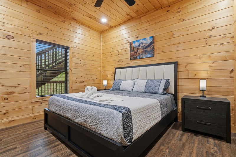 Cozy log cabin bedroom with plush bedding and scenic mountain views through your private window.