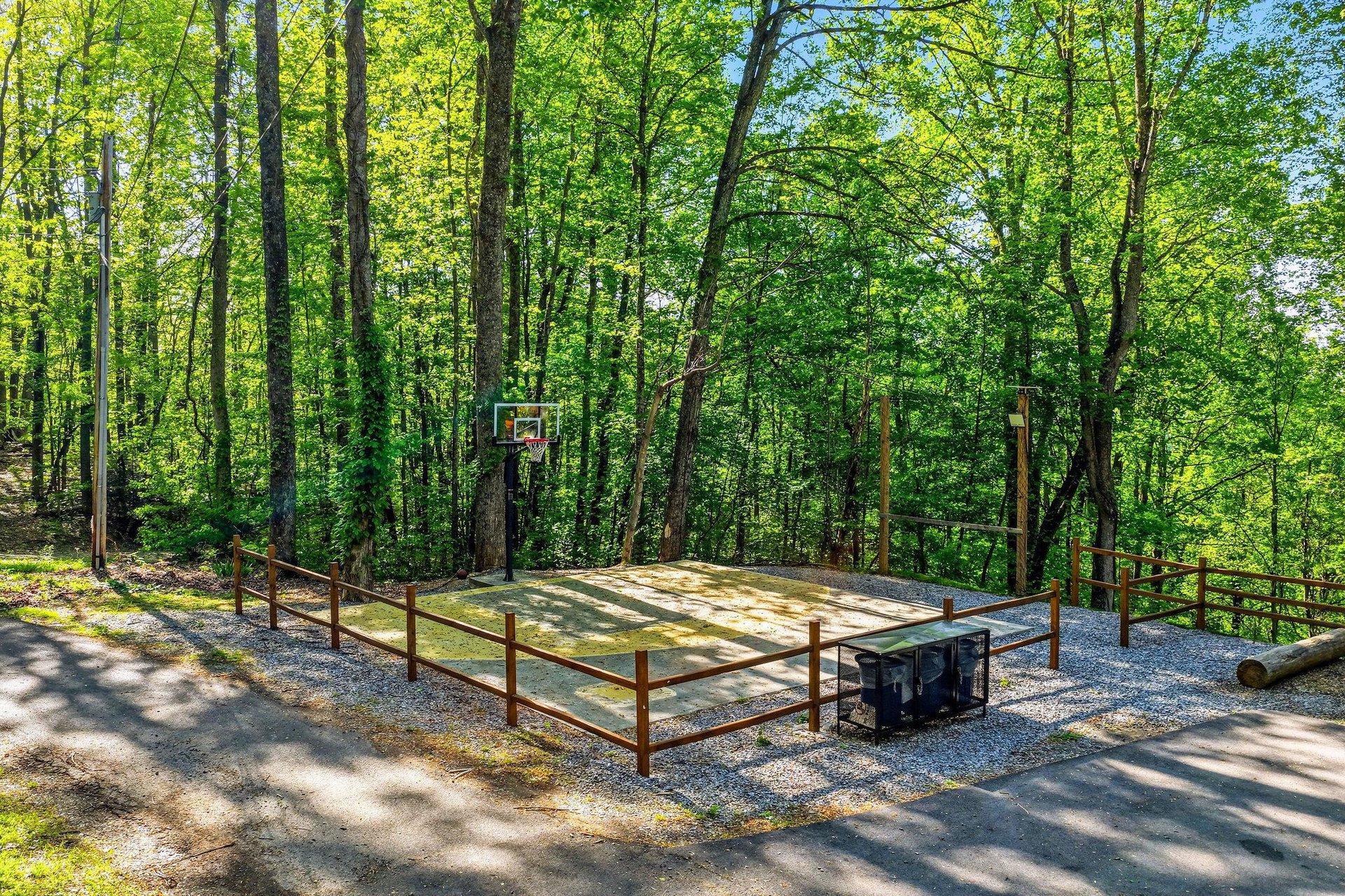 Outdoor basketball court surrounded by lush forest creates the perfect setting for active recreation during your stay.