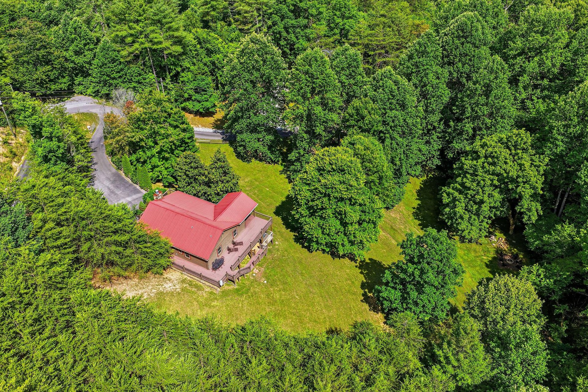 Aerial view of a charming property nestled within lush forest and natural greenery, offering peaceful seclusion and scenic surroundings.