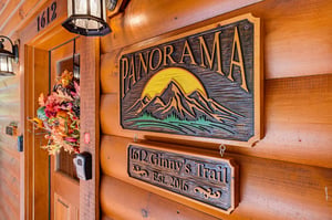 Wooden carved signs mark the entrance to Panorama cabin, nestled on Ginnys Trail with mountaininspired details welcoming guests to this established 2016 retreat.