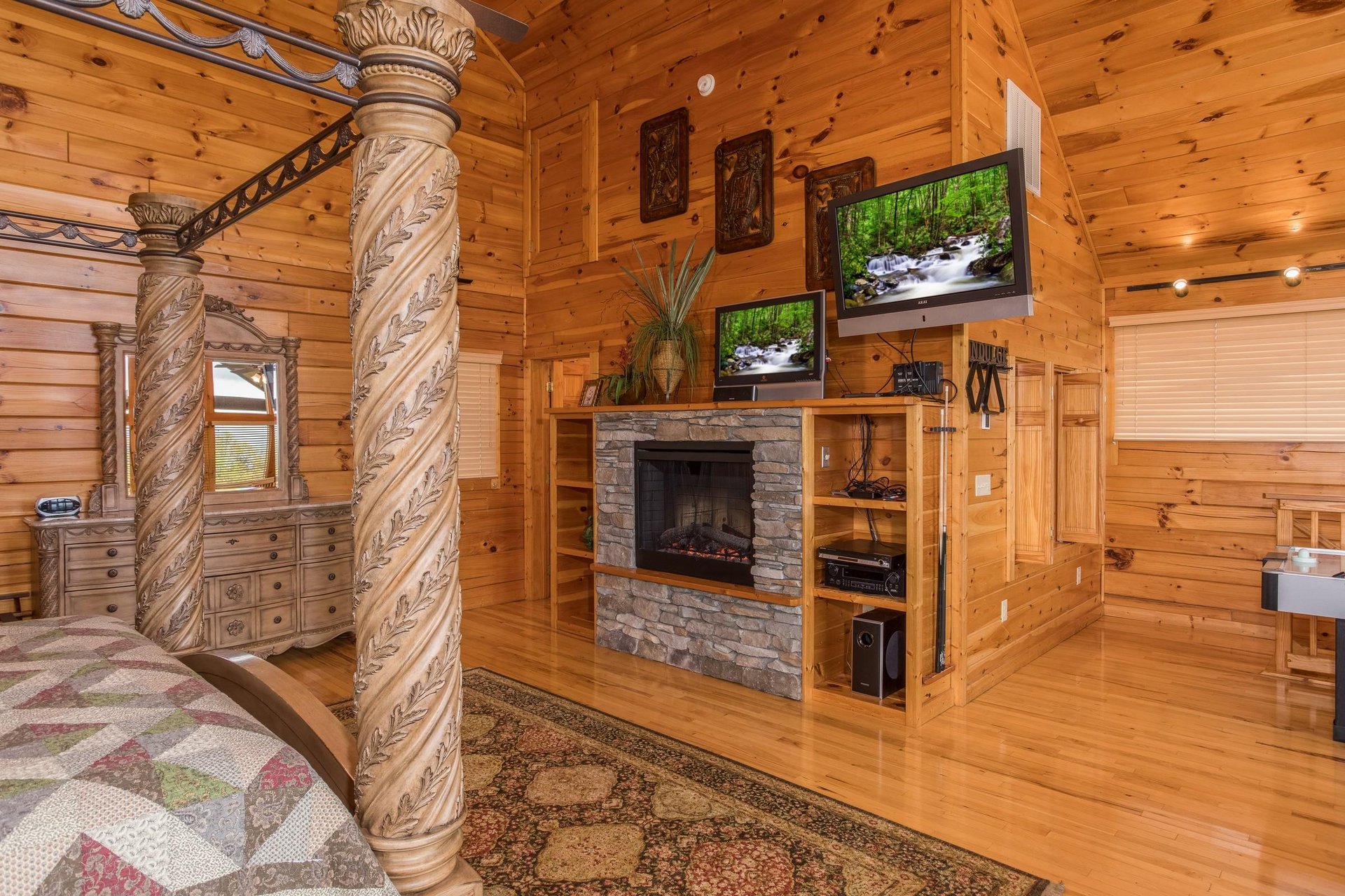Loft room with a king canopy bed, fireplace, and two TVs at Howlin in the Smokies, a 2 bedroom cabin rental located in Pigeon Forge