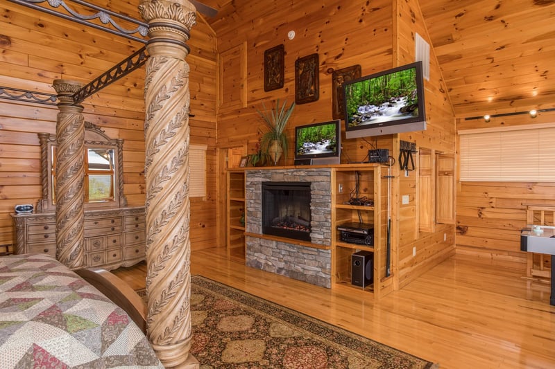 Loft room with a king canopy bed, fireplace, and two TVs at Howlin in the Smokies, a 2 bedroom cabin rental located in Pigeon Forge