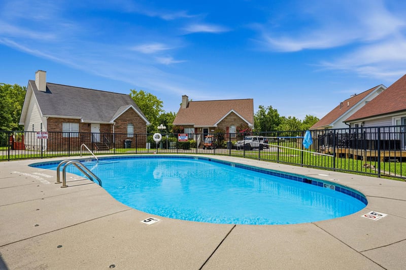 Sparkling community pool surrounded by residential buildings and lush greenery, providing a refreshing retreat during sunny days. Fenced for privacy and safety, with easy poolside access.