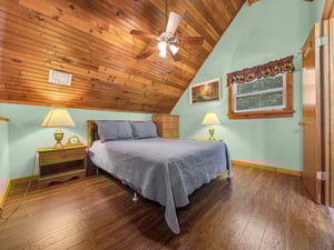 Your cozy bedroom features warm wood ceilings, soft bedside lighting, and peaceful mountain views through the window.