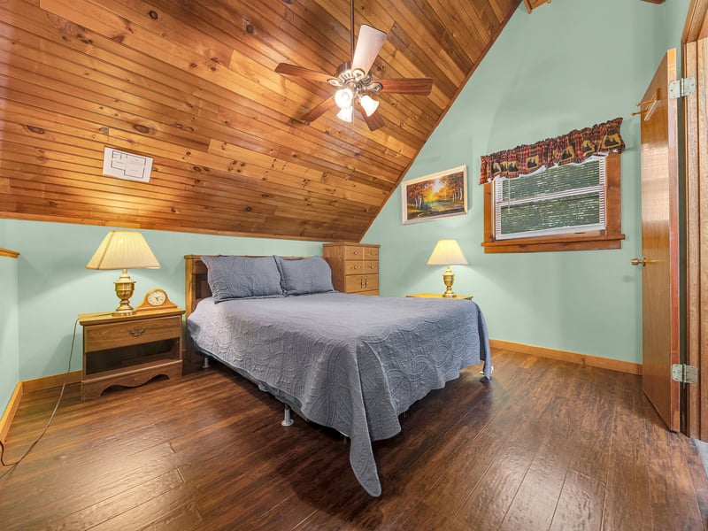 Your cozy bedroom features warm wood ceilings, soft bedside lighting, and peaceful mountain views through the window.