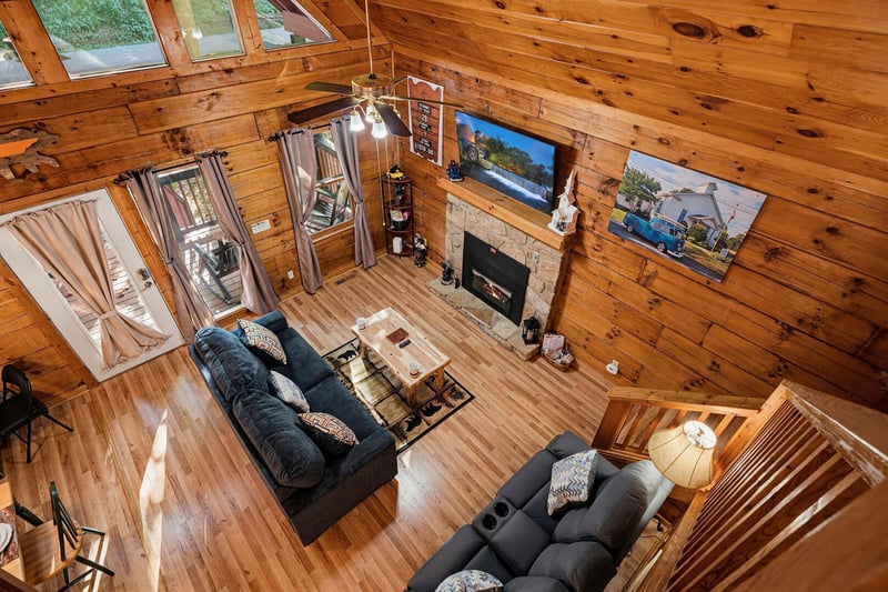 Sunlight pours through tall windows into your openconcept living space, where rich wood beams soar overhead and a stone fireplace anchors the room. Sink into plush couches and feel completely at home