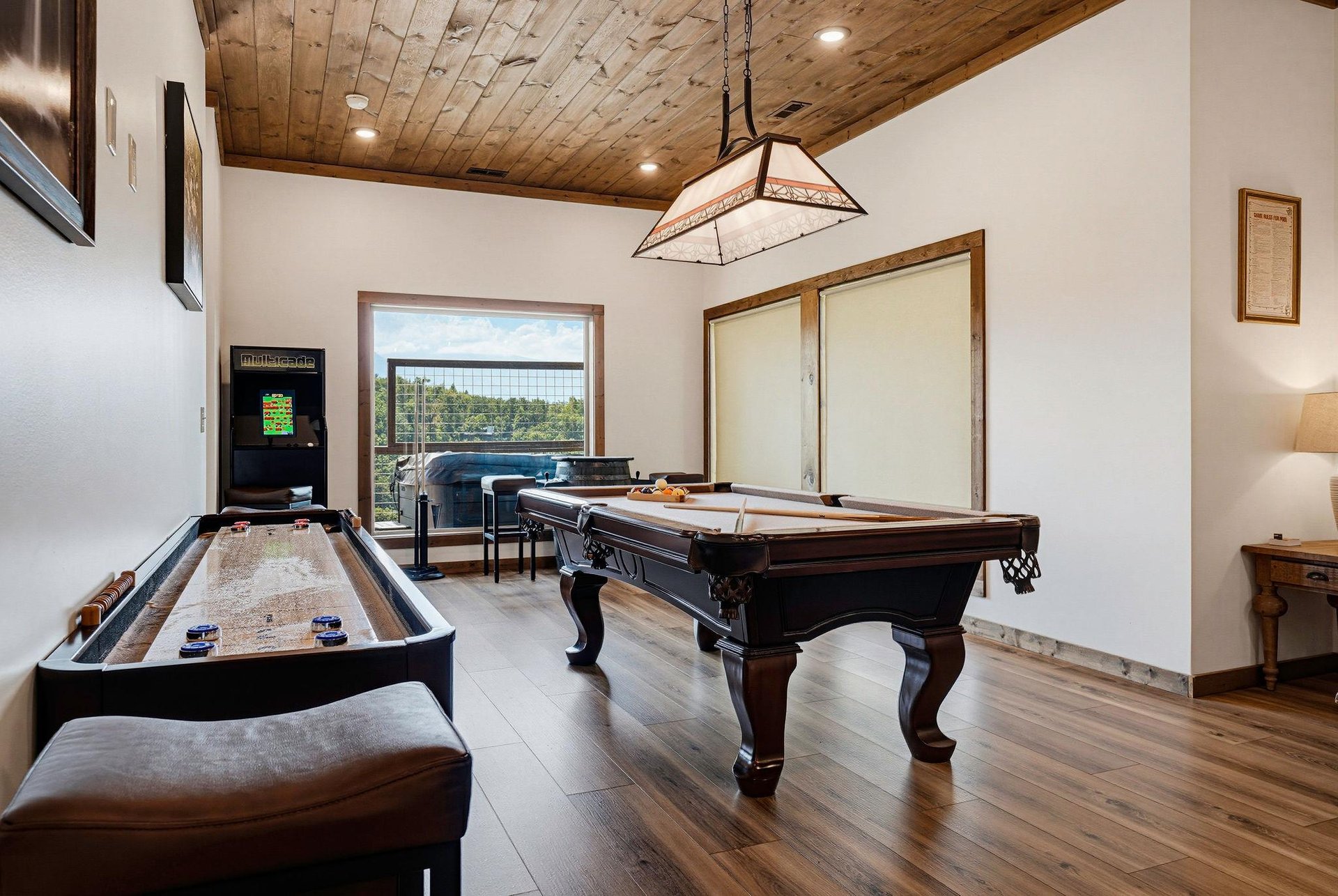 Your private game room awaits—complete with billiards, shuffleboard, and arcade fun under warm woodbeam ceilings, all just steps from your vacation retreat.