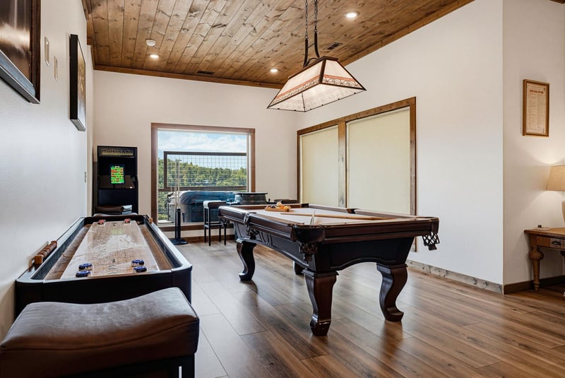 Your private game room awaits—complete with billiards, shuffleboard, and arcade fun under warm woodbeam ceilings, all just steps from your vacation retreat.