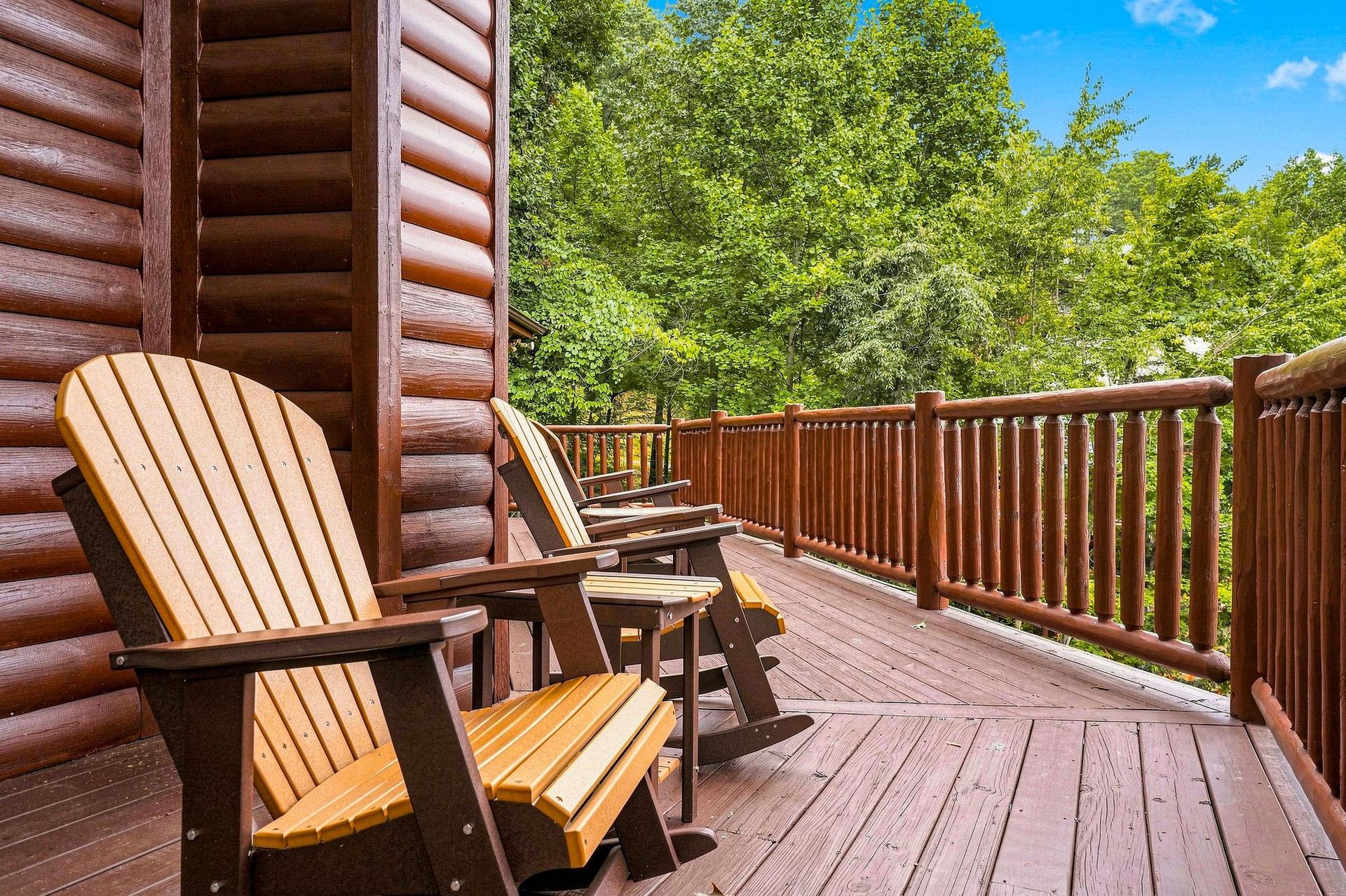 Your private deck invites you to unwind in classic Adirondack chairs, surrounded by lush forest views and warm summer sunshine.