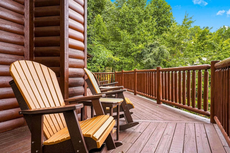 Your private deck invites you to unwind in classic Adirondack chairs, surrounded by lush forest views and warm summer sunshine.