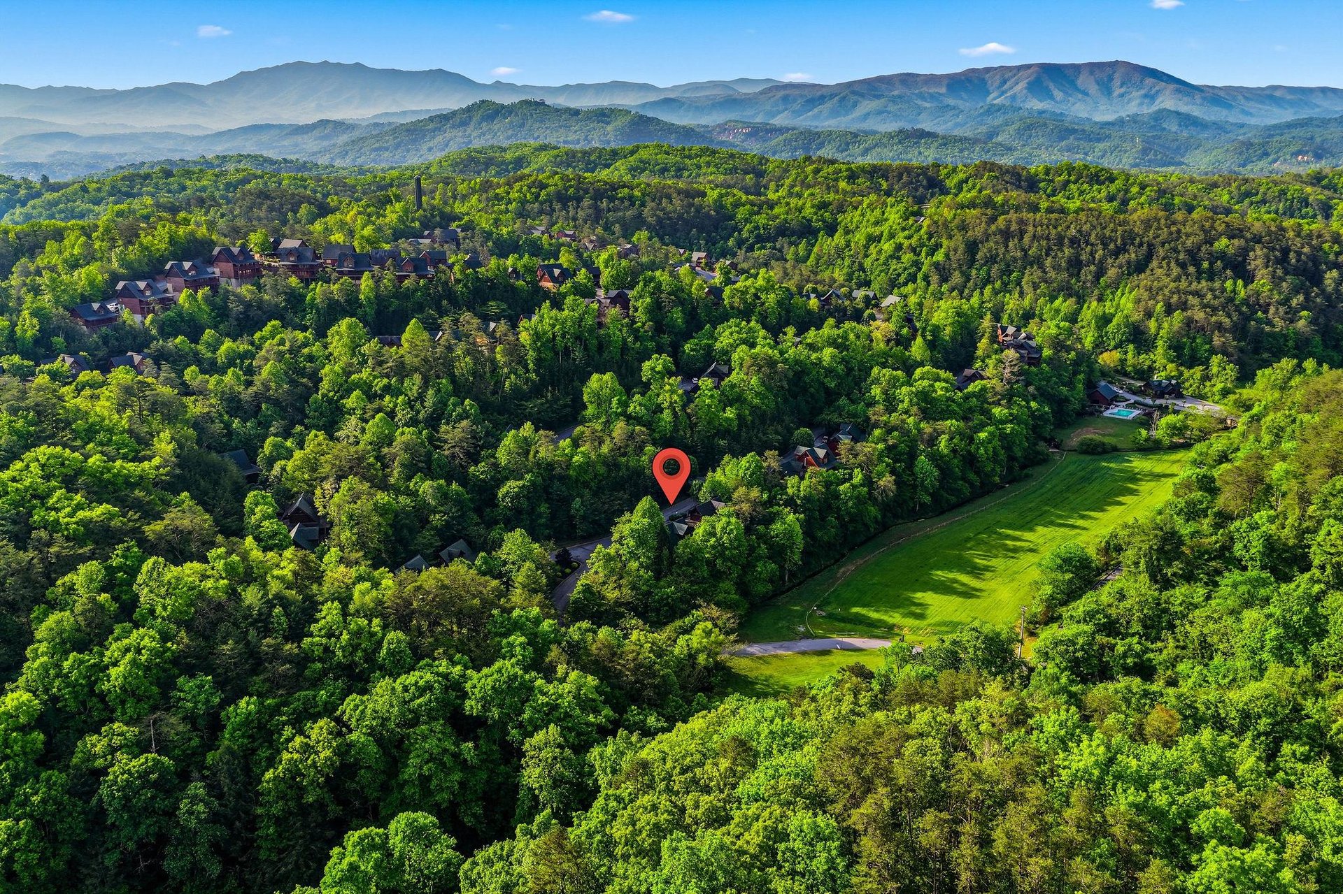 Aerial view showcases the propertys location within a lush mountain landscape, nestled among rolling hills and verdant forests.