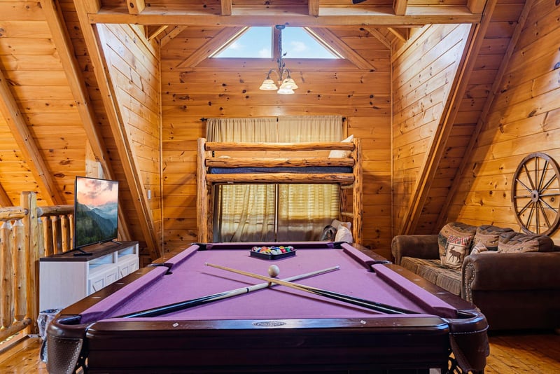 Challenge your travel companions to a game of pool in this warm cabin loft, where rustic wooden beams and a cozy bunk above create your own mountain retreat.
