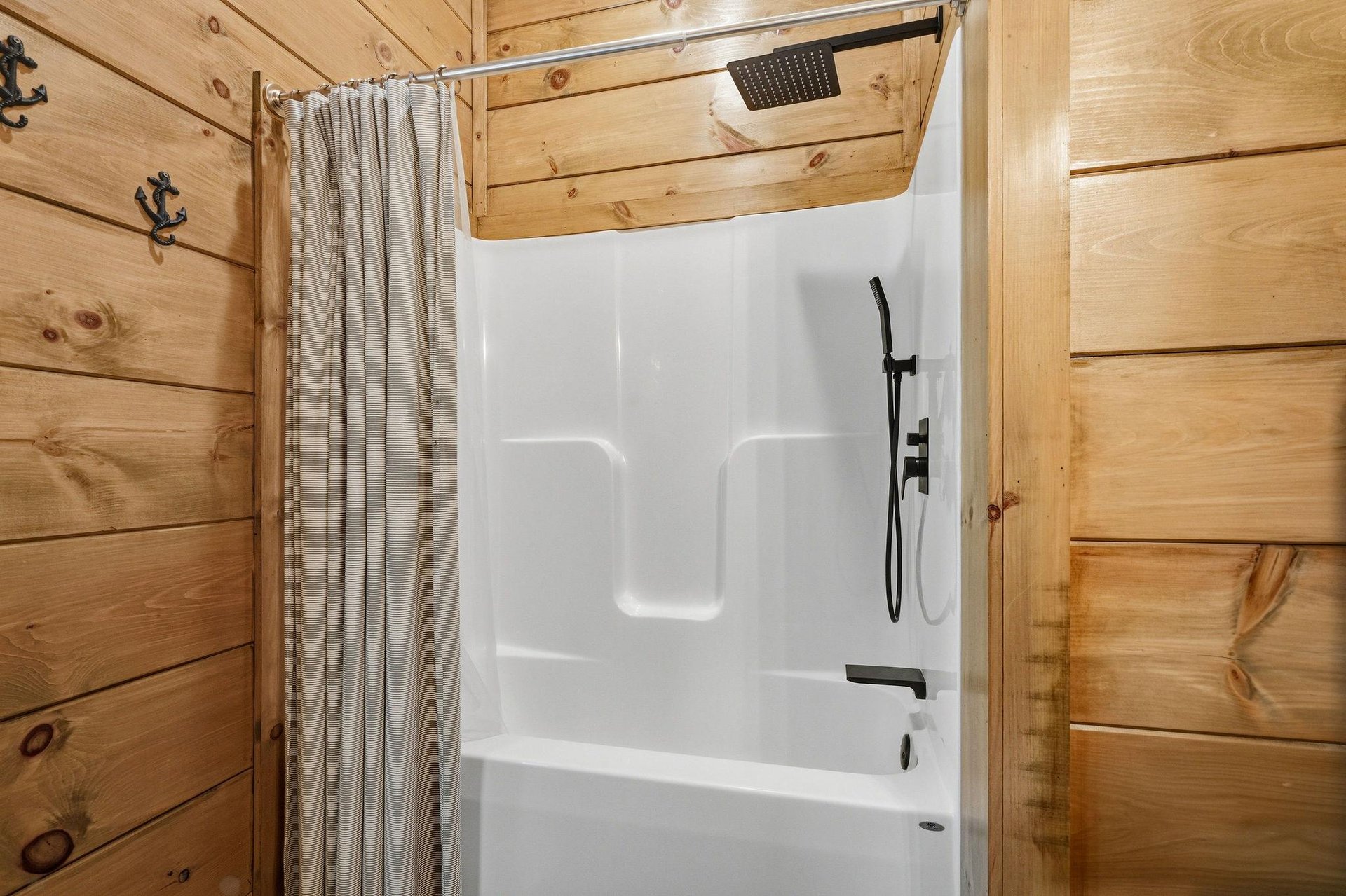 Rustic charm meets modern comfort in your private bathroom, where natural wood walls create a cozy cabin atmosphere around your pristine shower.
