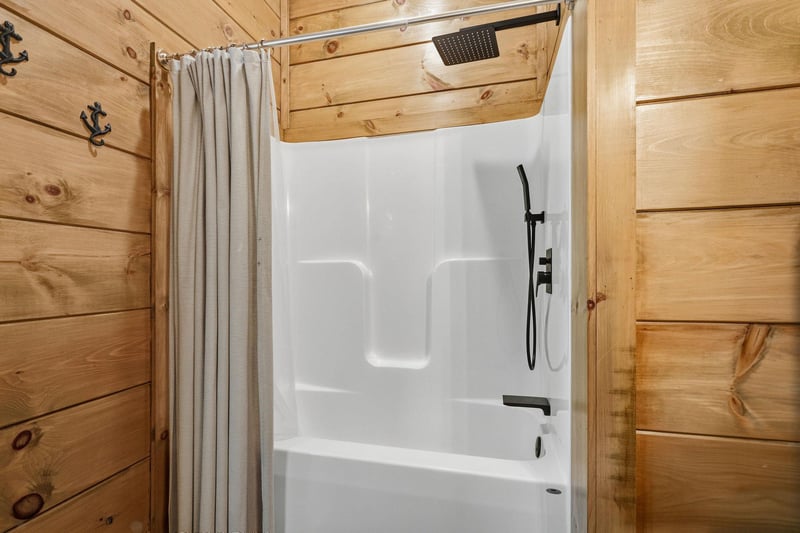 Rustic charm meets modern comfort in your private bathroom, where natural wood walls create a cozy cabin atmosphere around your pristine shower.
